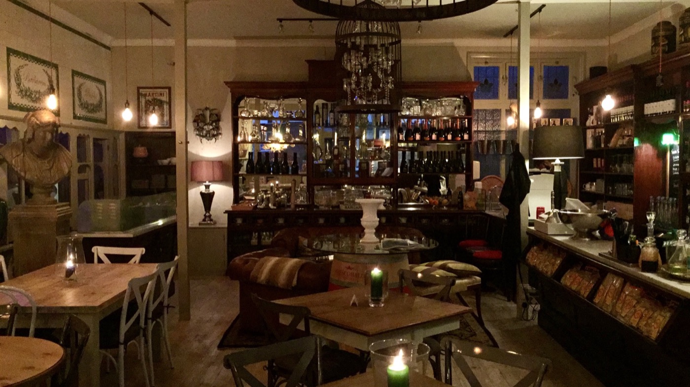 The warm interior of The Vinarium, with wooden tables, low lighting, bottles and historic fittings