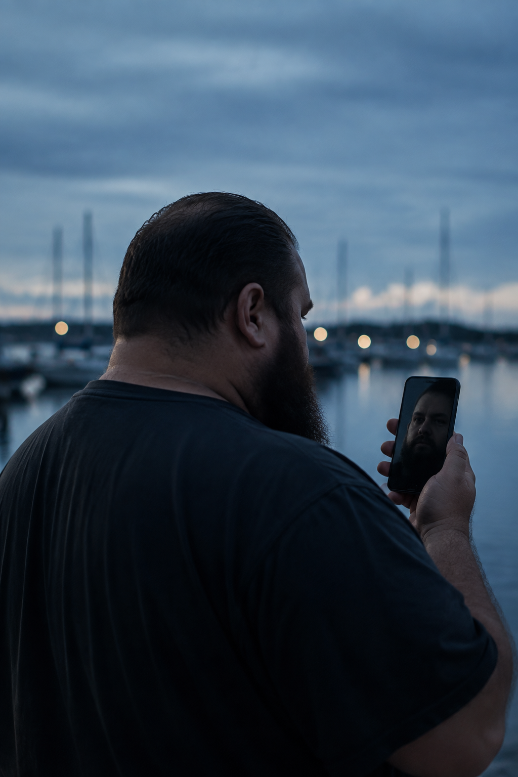 Un uomo immaginario guarda il proprio riflesso su uno smartphone, davanti a un porto al crepuscolo